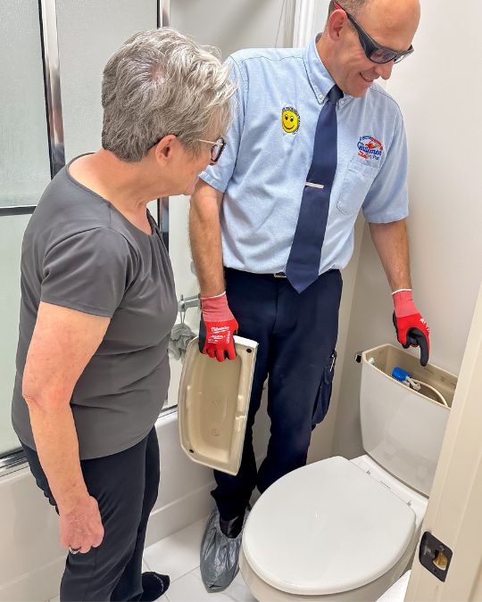 Plumber showing a customer a toilet repair